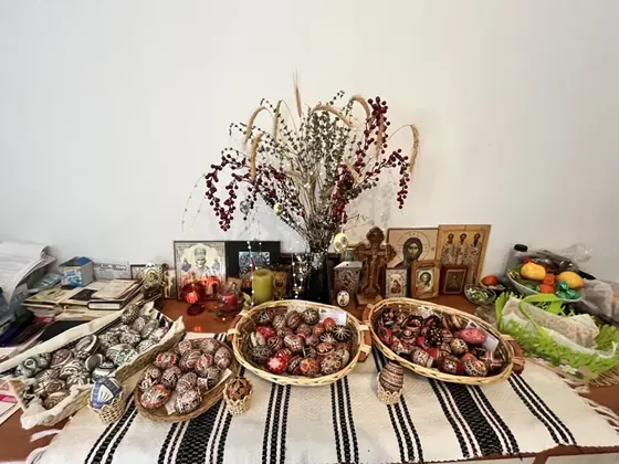 Baskets of intricately decorated eggs and a tree of hanging eggs arranged on a woven tablecloth.