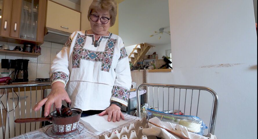 Person painting the egg in black dye.