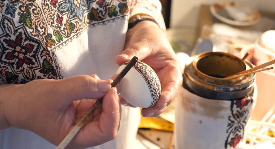 Person painting intricate design on egg
