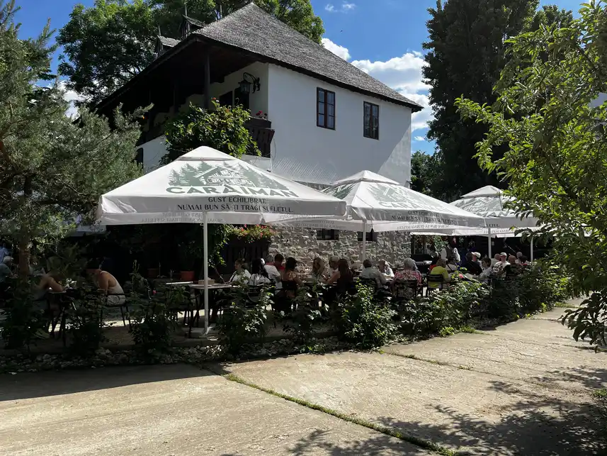 Outdoor dining terrace inside the museum grounds, with the Caraiman sign.