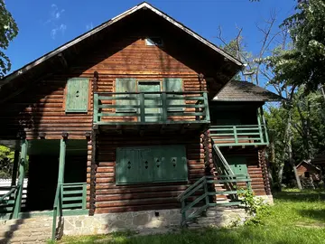 Wooden mountain house with a deep porch and upper balcony.