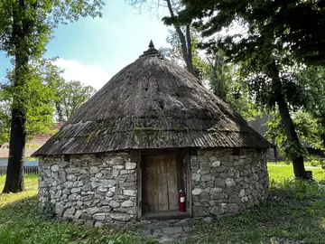 Small stone storage building with a steep roof.