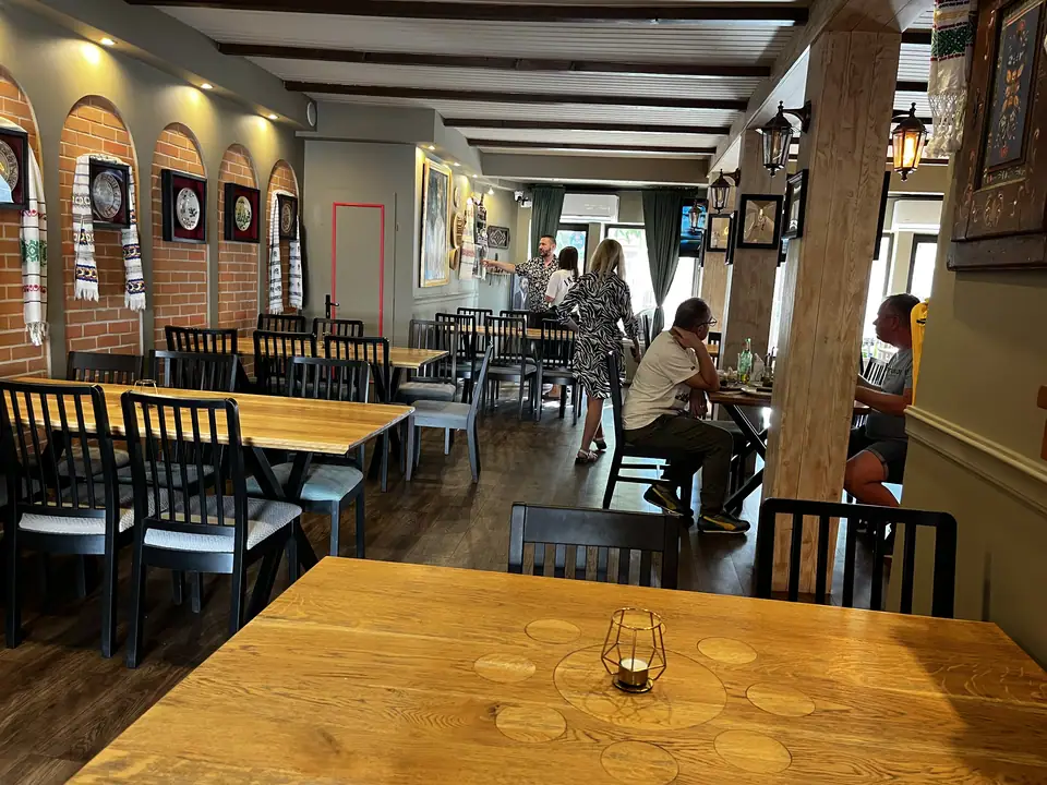 Long dining room at Restaurant Ceaun decorated with Romanian textiles and wall plates.