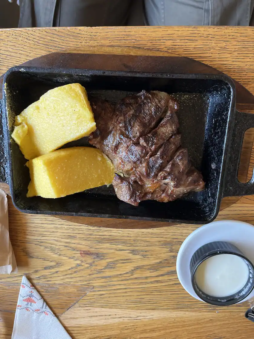 Grilled meat pieces with polenta on a cast-iron platter at Restaurant Ceaun.