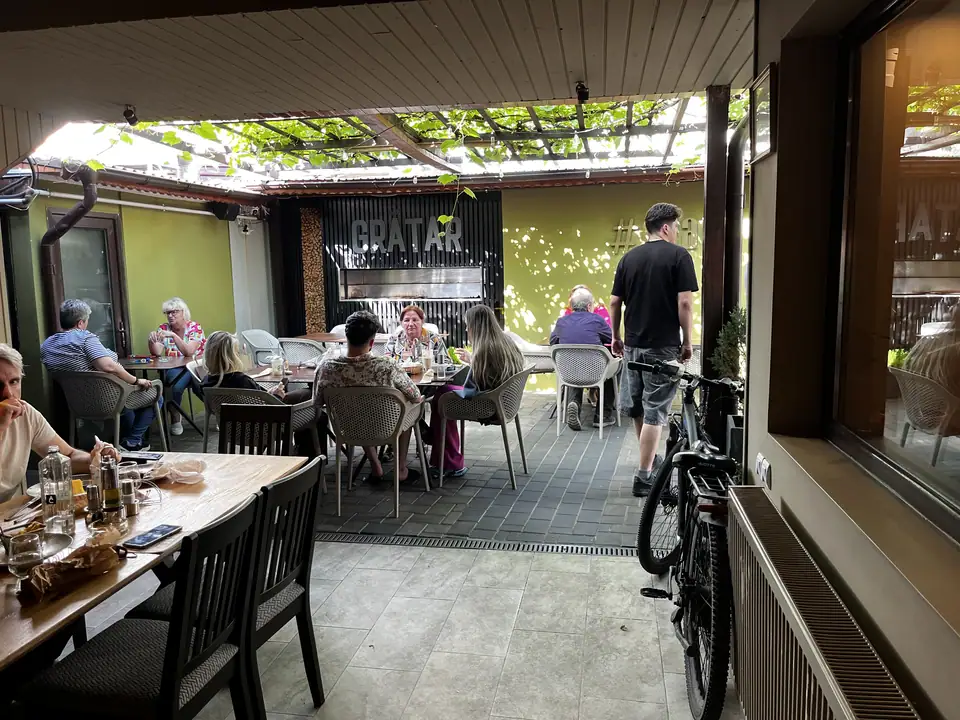 Diners on Restaurant Ceaun’s covered outdoor terrace under grape leaves.