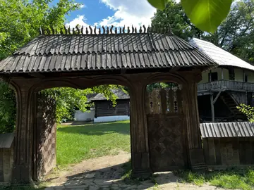 Carved wooden gate with village houses behind it.