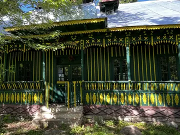 Dark green veranda decorated with yellow carved details.