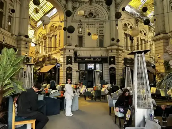Yellow glass roof and ornate upper façades around the central rotunda of Macca–Villacrosse Passage in Bucharest.