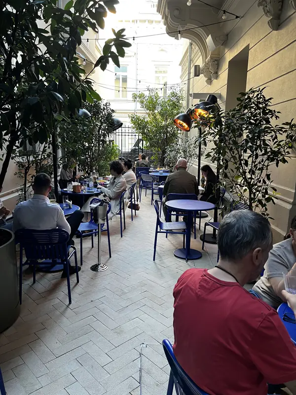 Guests seated at tables among plants in the narrow courtyard at Casa Mița Biciclista