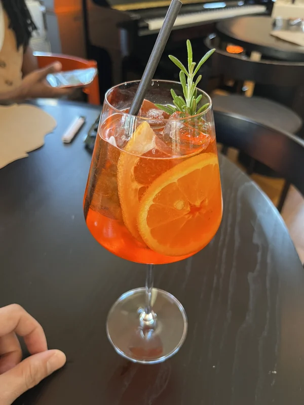 Orange drink with ice, a citrus slice and herb garnish at La Mița Biciclista