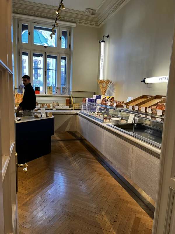Pastries displayed in a glass counter below tall windows at La Mița Biciclista