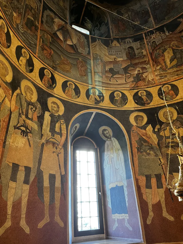 Frescoes and painted figures surrounding a tall window in Kretzulescu Church.