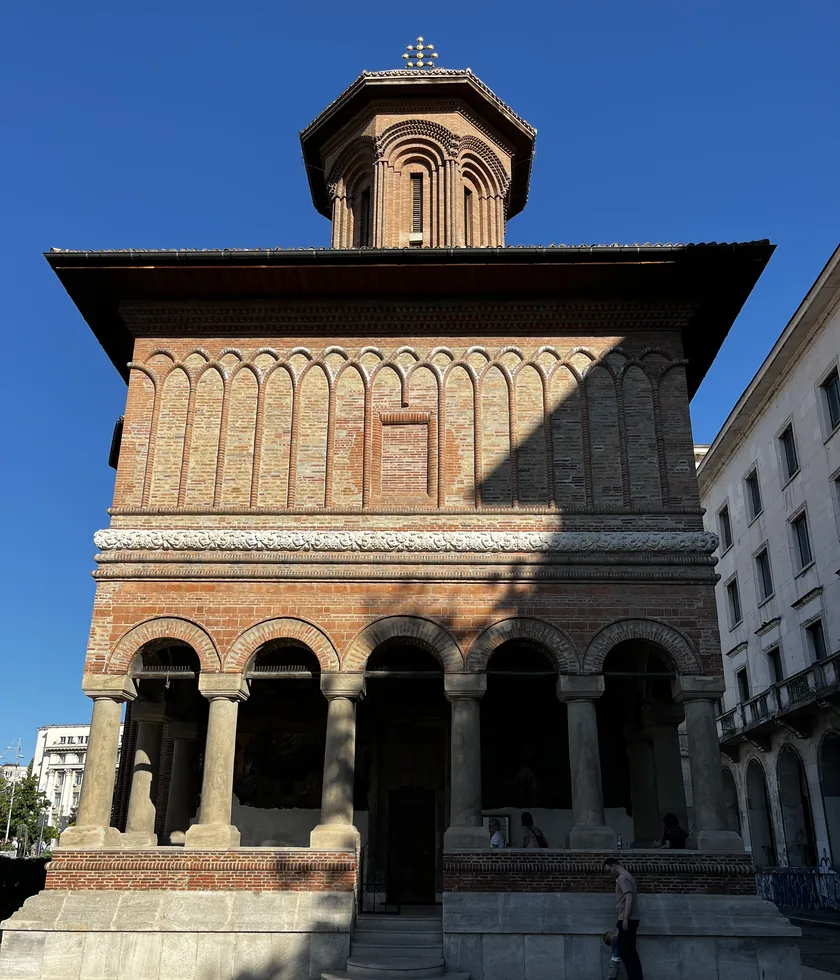 Front of Kretzulescu Church with its red-brick tower, arched stone porch and central entrance.