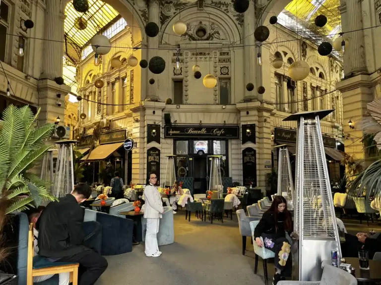 Yellow glass roof and ornate upper façades around the central rotunda of Macca–Villacrosse Passage in Bucharest.