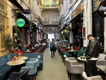 Bistro awning, café tables and shop signs along Macca–Villacrosse Passage.