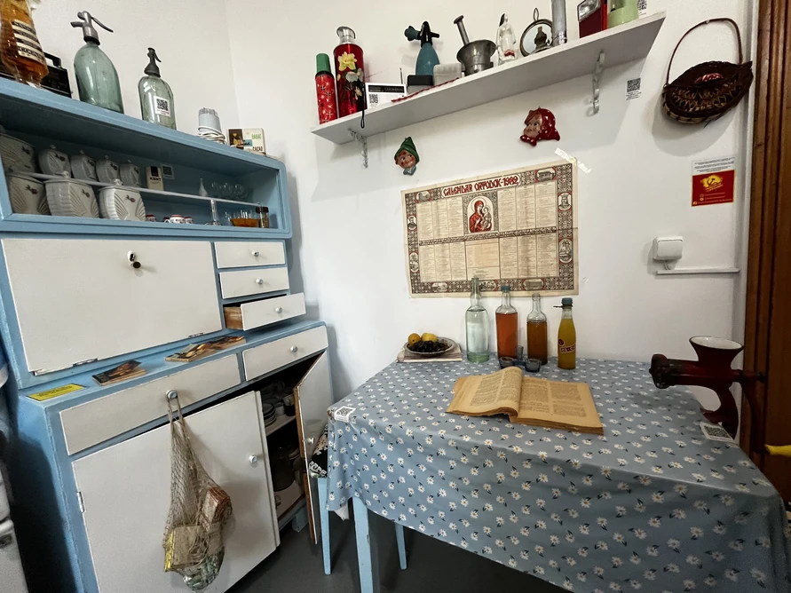 Blue kitchen cabinet, enamel dishes, siphon bottles and a table in the Museum of Communism in Bucharest.