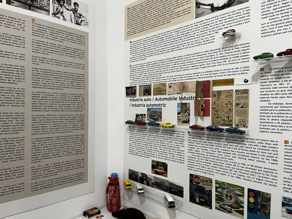 Model cars mounted beside a museum panel about the automobile industry.