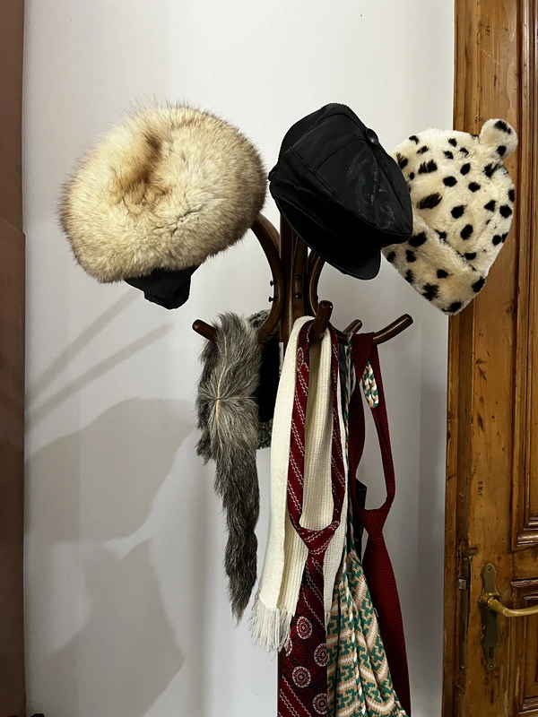 Vintage hats, scarves and patterned clothing hanging on a coat stand.