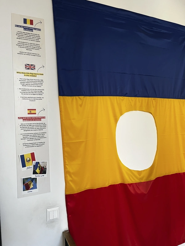 Romanian tricolour with a hole in its yellow stripe and a multilingual explanatory panel.