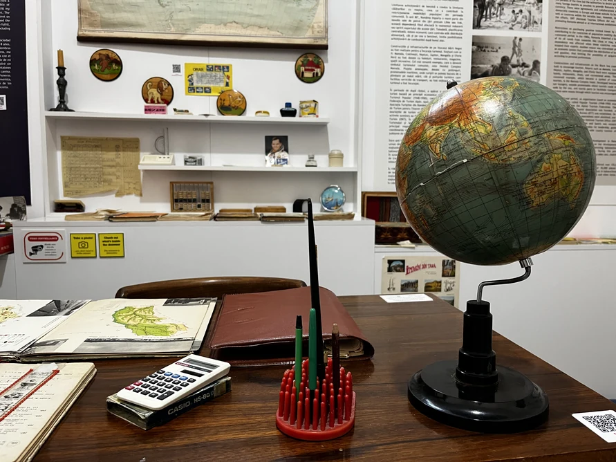 Wooden school desk with a globe, abacus, calculator, books and notebooks.