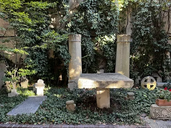 Carved stone columns and crosses among greenery in the Stavropoleos courtyard.